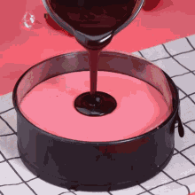 chocolate sauce is being poured over a pink cake