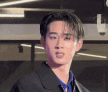 a young man wearing a black jacket and a blue shirt is sticking his tongue out .