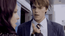 a young man in a suit and tie is talking to a woman .