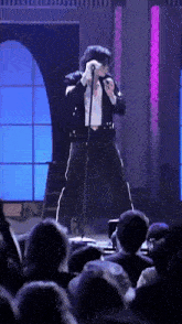 a man singing into a microphone while standing in front of a crowd