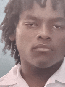 a young man with curly hair looks at the camera