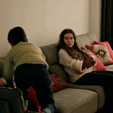 a girl sits on a couch with a pillow that says native american on it