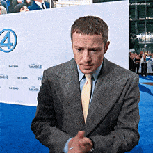 a man in a suit and tie is standing in front of a sign that says fantastic four