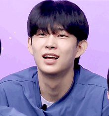 a close up of a young man 's face with a purple background