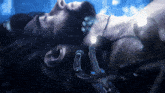 a man with long hair and a beard is laying in a dark room with a gameclipe logo on the bottom right