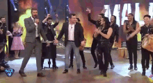 a group of people are dancing on a stage in front of a sign that says ' aguila '