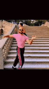a man in a pink shirt is dancing on stairs