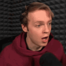 a man in a red hoodie has his mouth wide open