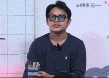 a man wearing glasses is standing in front of a wall that says the grid network hub