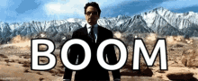 a man in a suit and tie stands in front of a mountain with the word boom written in white