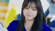 a close up of a woman wearing a blue shirt and a blue necklace .