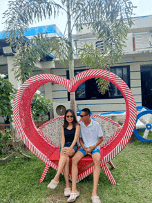 a man and a woman sit on a heart shaped chair