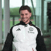 a man wearing a manchester united jacket smiles