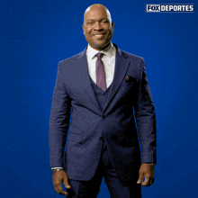 a man in a suit and tie is standing in front of a blue background with fox deportes written on it