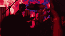 a woman singing into a microphone in front of a red background