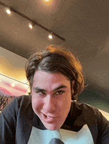a young man making a funny face wearing a black shirt with a white s on it