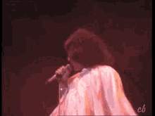 a man is singing into a microphone on a stage in a dark room .