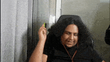 a man with long curly hair is sitting in a chair with headphones and a pen in his mouth .