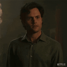 a man is standing in front of a chandelier in a dark room and looking at the camera .