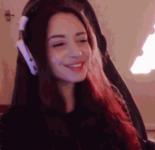 a woman wearing headphones is smiling and looking at the camera