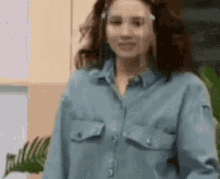 a woman wearing a blue shirt and sunglasses is smiling .
