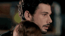 a man with a beard and curly hair looks at a woman