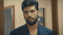a man with a beard is standing in front of a door in a room .