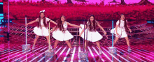 a group of young girls in white dresses are dancing on a stage .