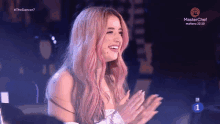 a woman with pink hair is applauding in front of a master chef logo