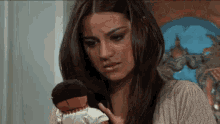 a woman is holding a doll in her hands and looking at it