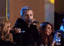 a man is singing into a microphone while a woman watches