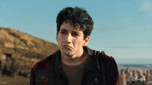 a man with green hair is wearing a plaid shirt and a disney + jacket