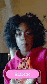 a woman in a pink hoodie is holding a slice of pizza and the word block is above her head