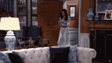 a woman standing in a living room looking at her cell phone
