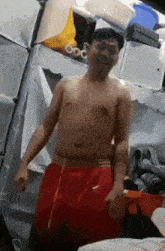 a shirtless man in red nike shorts is standing in a room