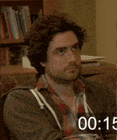 a man sitting on a couch with a countdown of 00:15 behind him