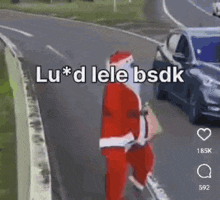 a man dressed as santa claus is walking down the side of a road next to a car .