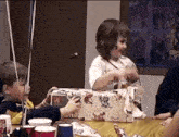 a little girl sitting at a table holding a box that says saturday
