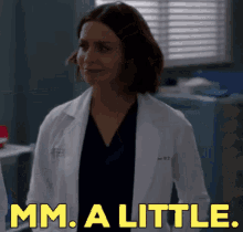 a woman in a lab coat is standing in a room with the words mm a little .