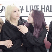 a couple of girls are hugging each other in front of a sign that says live hall