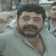 a man with a beard is smoking a cigarette and making a face .