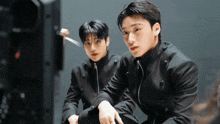two boys in black jackets are sitting next to each other