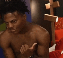 a shirtless man is sitting on a bed with his hand on his chest