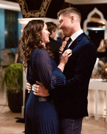 a man in a suit and a woman in a blue dress are dancing