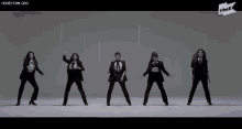 a group of women in suits are dancing in front of a sign that says the k