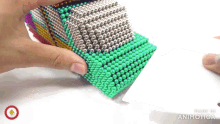 a person is playing with a stack of magnetic beads that are made by animatica