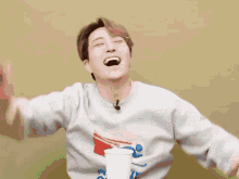 a man wearing a sweatshirt that says coca cola is laughing with his arms outstretched