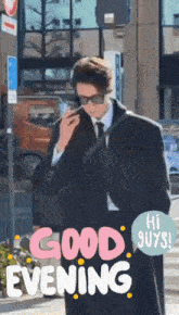 a man in a suit and tie is smoking a cigarette in front of a sign that reads good evening