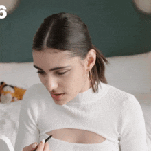 a woman in a white sweater is looking at herself in a mirror