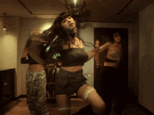 a woman in a black top and shorts is dancing in a dark room
